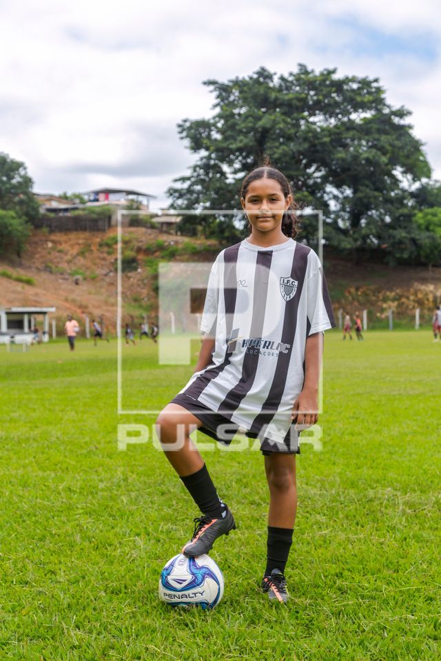 Menina posando com bola durante treino em time de futebol feminino