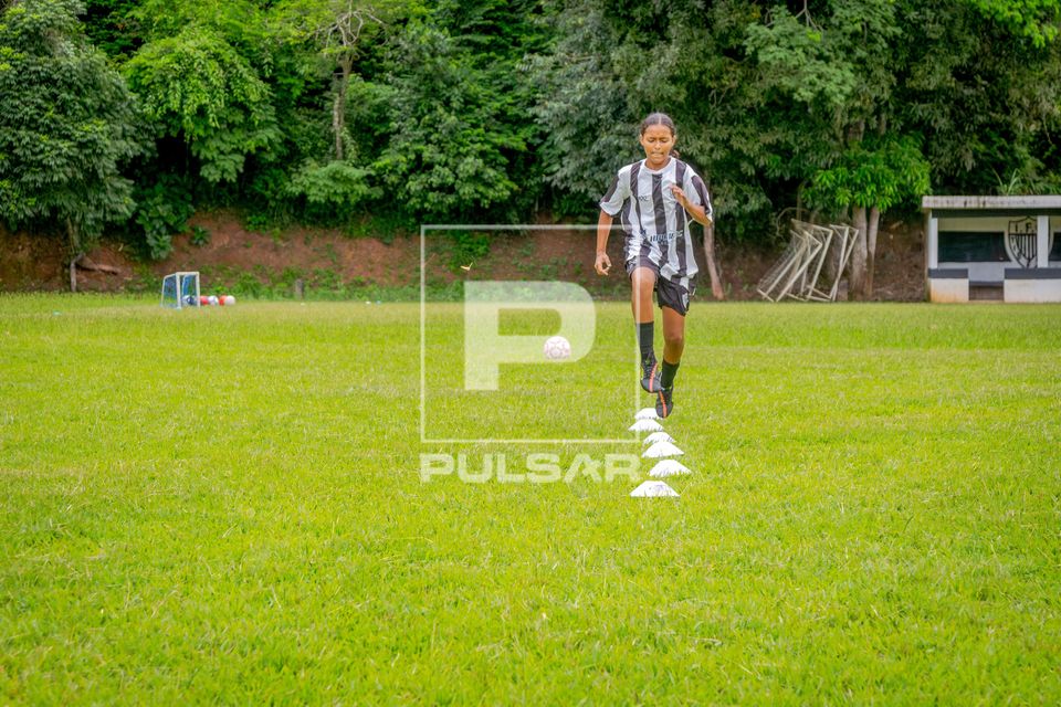 Menina se exercitando durante treino de time de futebol feminino
