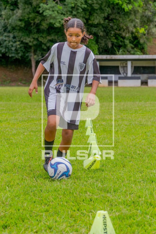 Menina fazendo atividade com bola durante treino de time de futebol feminino