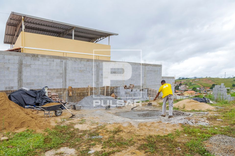 Servente de pedreiro preparando massa de cimento para obra 