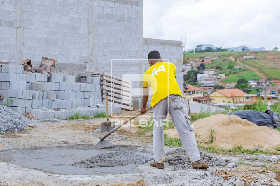 Servente de pedreiro preparando massa de cimento para obra 