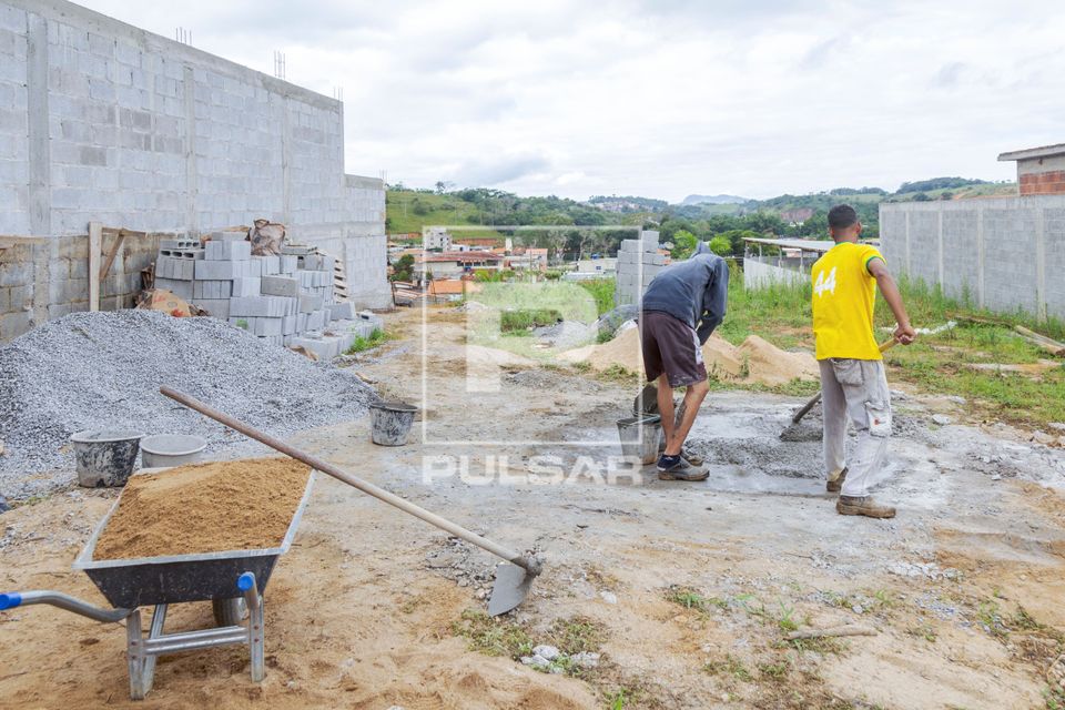 Serventes de pedreiro preparando massa de cimento para obra 