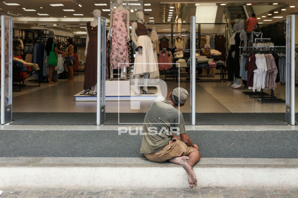 Morador de rua na entrada de loja de roupas