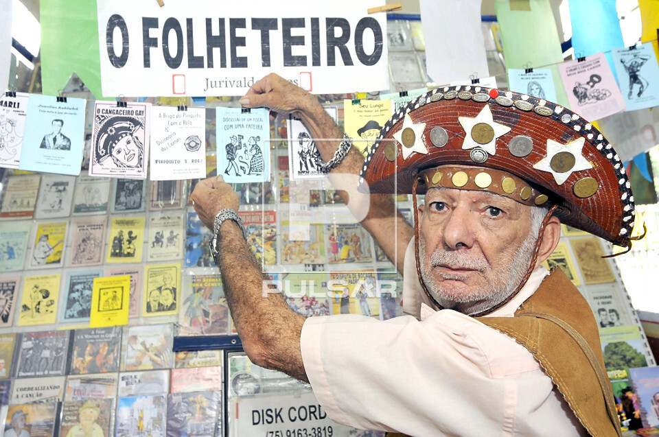 Escritor e folheteiro de literatura de cordel mostrando folhetos - 