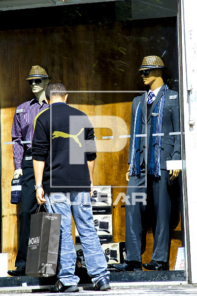 Homem olhando vitrine de loja com roupas masculinas de inverno