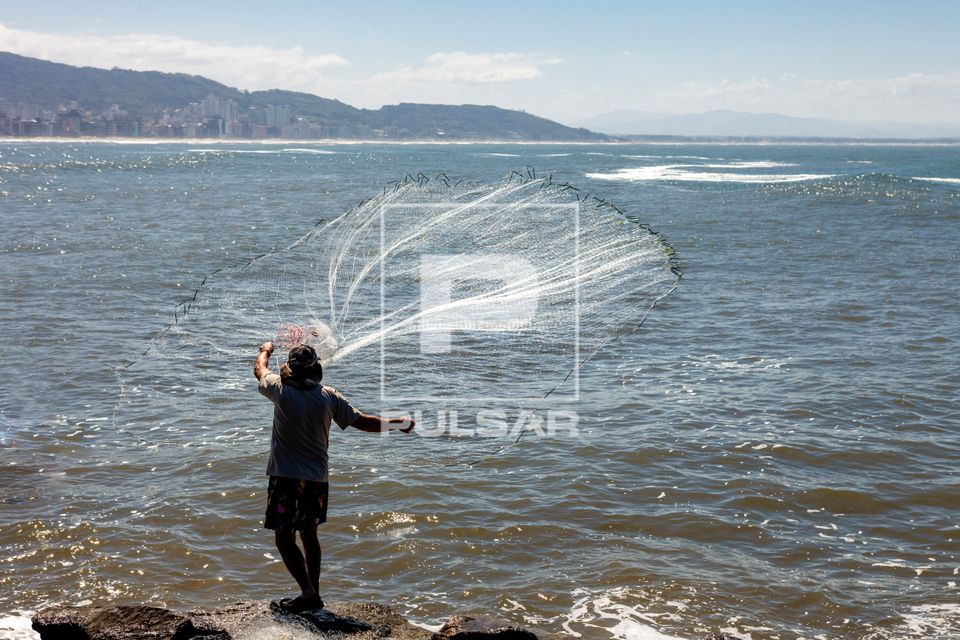 Pescador artesanal arremessando tarrafa no Mar Grosso