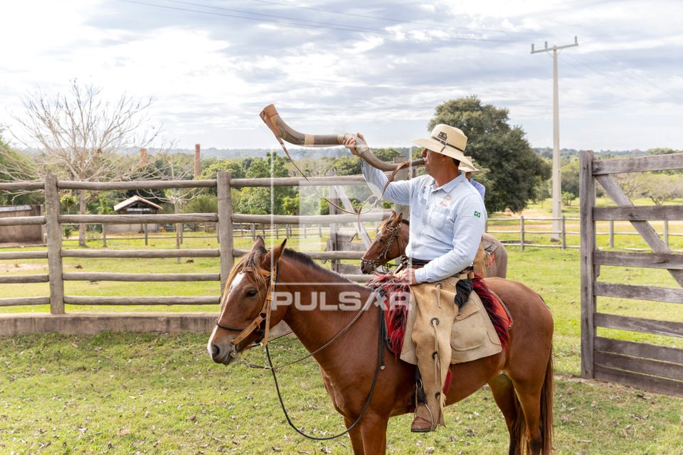 Guia pantaneiro tocando berrante para iniciar cavalgada com turistas em hotel fazenda