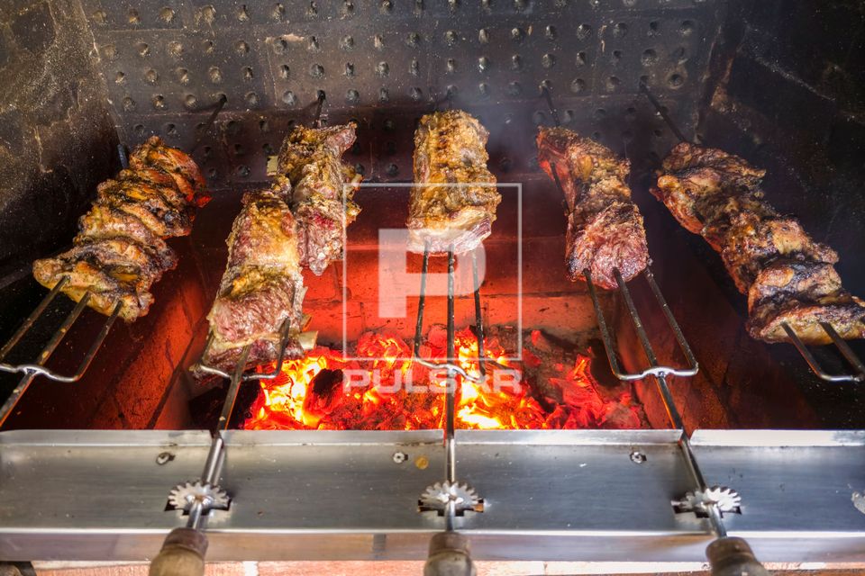 Churrasco sendo assado em churrasqueira rotativa