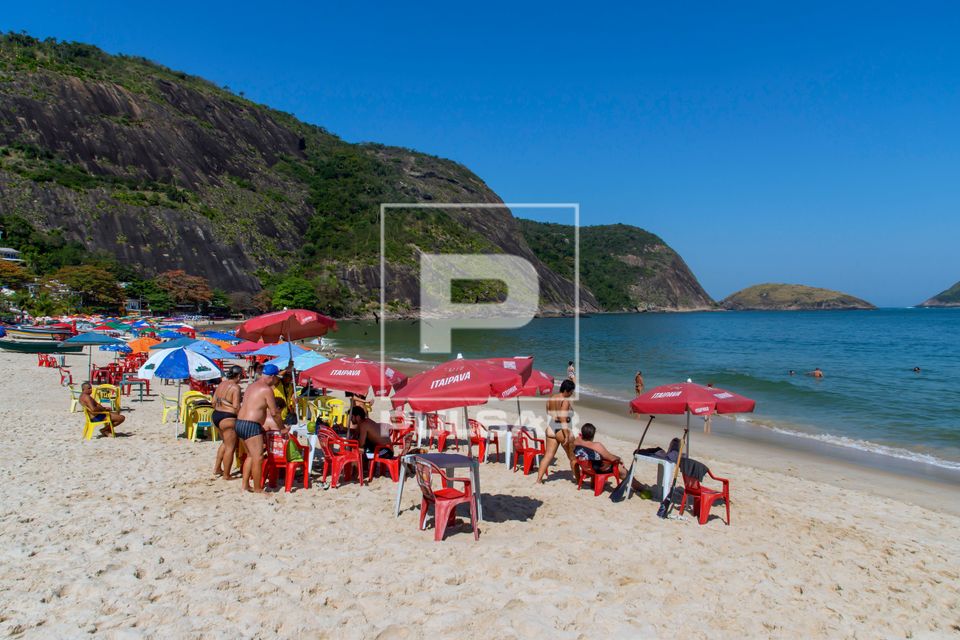 Pessoas em mesas de bar na Praia de Itaipu 