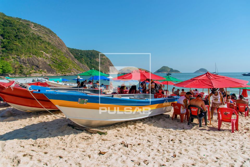 Barcos e pessoas em mesas de bar na Praia de Itaipu 