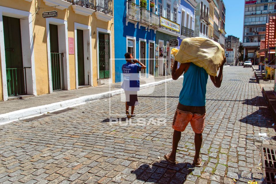 Homem carregando saco de carga nas costas na Praça da Sé