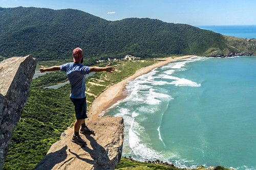 Pessoa de braços abertos no Morro da Coroa - ao fundo Praia da Lagoinha do Leste - Parque Municipal da Lagoin