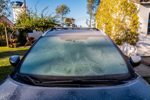 Vidro de veículo coberto de gelo causado por geada na zona rural