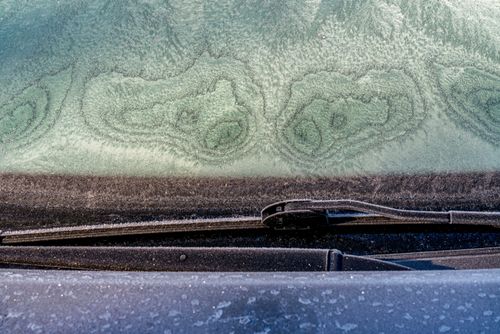 Vidro de veículo coberto de gelo causado por geada na zona rural
