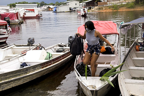 Passageira desembarcando de barco com máscara durante a pandemia de coronavírus de COVID-19 -