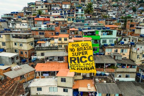 Vista de drone de moradias na Favela do Vidigal com faixa do Coletivo Alvorada - campanha pela taxação dos S