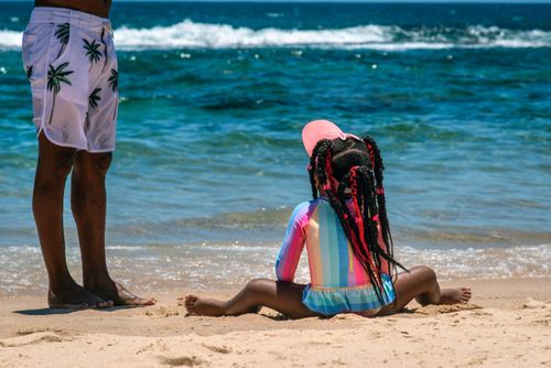 Pai ao lado de filha com roupa com proteção solar contra raios UV ultra violeta na Praia do Farol da Barra